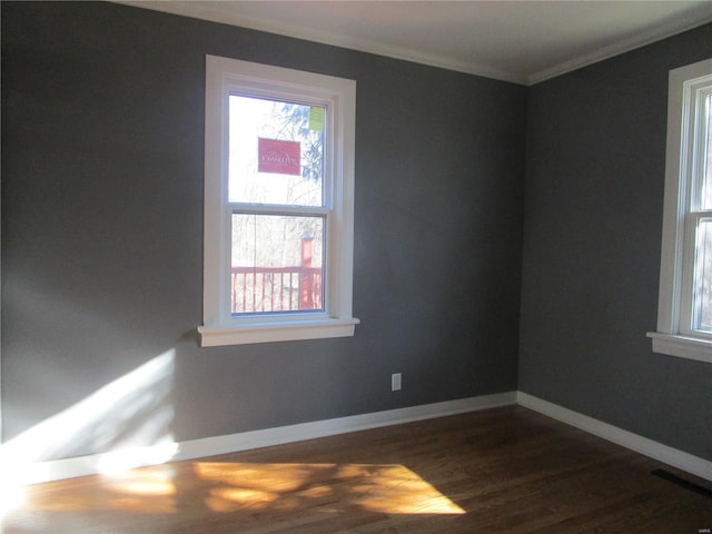 empty room featuring crown molding, visible vents, baseboards, and dark wood-type flooring