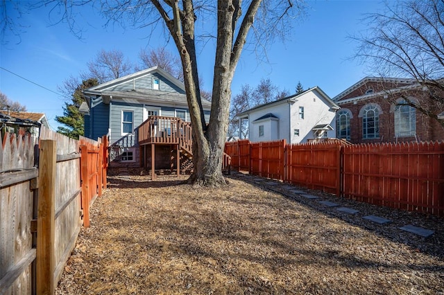 view of yard with a fenced backyard, a wooden deck, and stairs