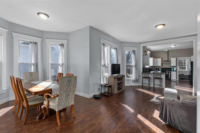 dining space featuring dark wood-type flooring and baseboards