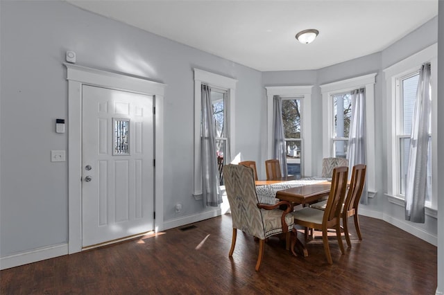 dining space featuring dark wood finished floors, visible vents, and baseboards