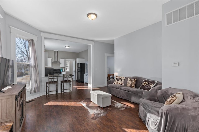 living room featuring dark wood-style flooring, visible vents, and baseboards