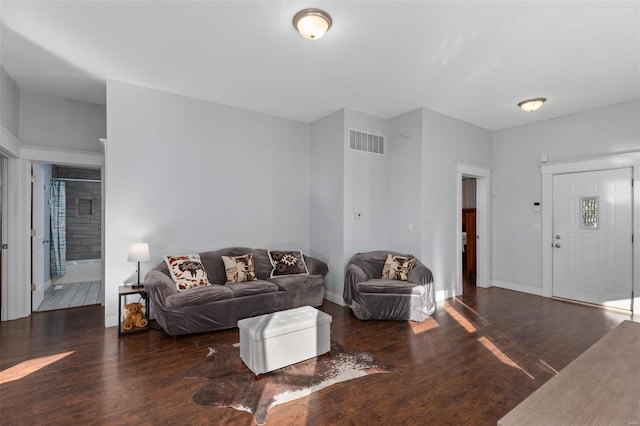 living room featuring baseboards, visible vents, and wood finished floors