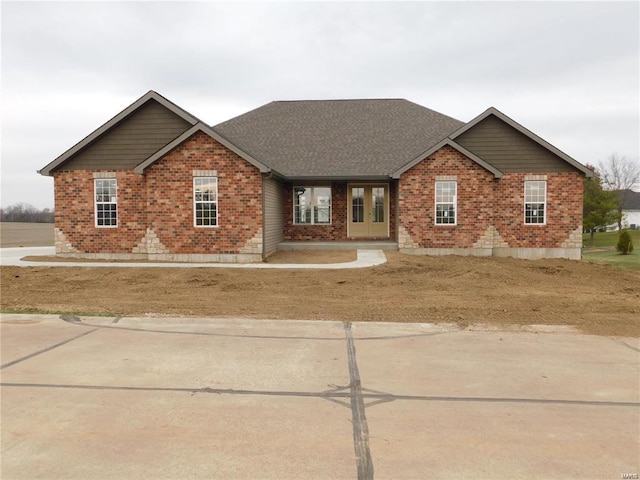 view of front of home with brick siding and roof with shingles