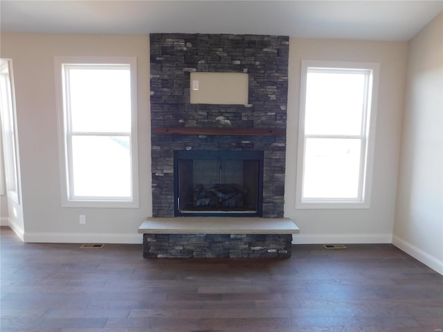 unfurnished living room featuring a fireplace, a wealth of natural light, and wood finished floors