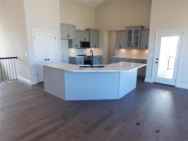 kitchen featuring dark wood-style floors, a large island, gray cabinets, appliances with stainless steel finishes, and a sink