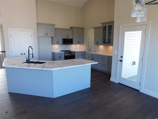 kitchen featuring high vaulted ceiling, gray cabinetry, electric range, a sink, and a large island with sink