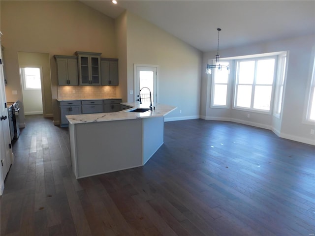 kitchen featuring dark wood-style flooring, a sink, glass insert cabinets, and gray cabinetry