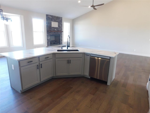 kitchen featuring a large fireplace, open floor plan, dark wood-type flooring, stainless steel dishwasher, and a sink