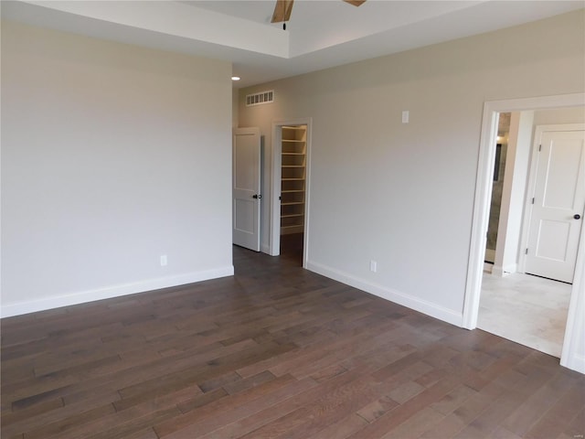 spare room with dark wood-style flooring, visible vents, and baseboards