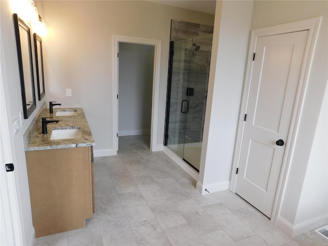 full bathroom featuring baseboards, double vanity, a sink, and a shower stall