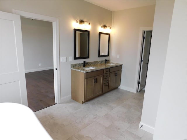 bathroom featuring double vanity, baseboards, and a sink