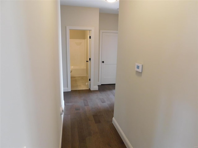 corridor with dark wood-style flooring and baseboards