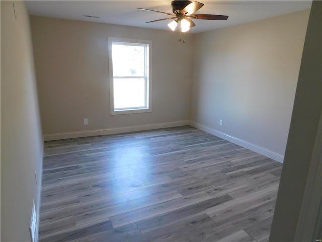 unfurnished room featuring ceiling fan, visible vents, baseboards, and wood finished floors