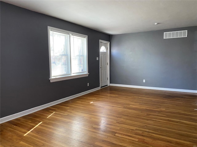 spare room featuring visible vents, baseboards, and wood finished floors