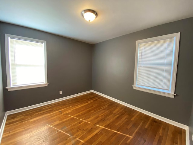 spare room with baseboards and dark wood-style flooring