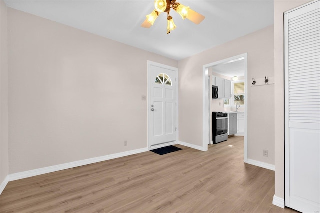 entryway featuring light wood-style flooring, baseboards, and ceiling fan