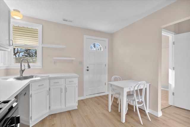 kitchen featuring visible vents, stove, light wood-style floors, open shelves, and a sink