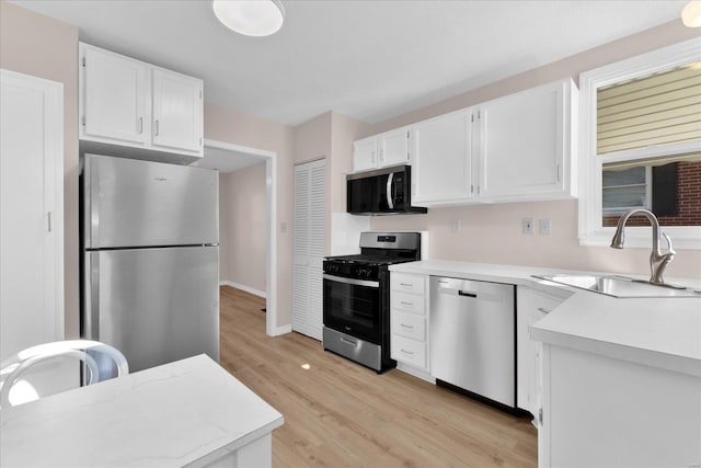 kitchen featuring white cabinetry, appliances with stainless steel finishes, light countertops, and a sink