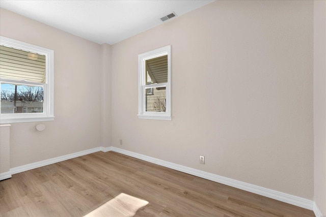 spare room with light wood finished floors, baseboards, and visible vents