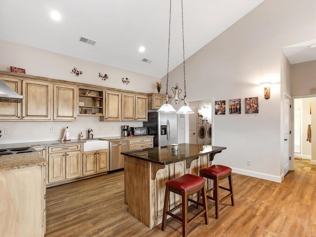 kitchen with open shelves, visible vents, appliances with stainless steel finishes, washing machine and dryer, and a sink