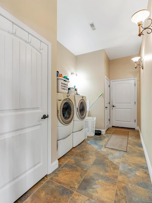 laundry room with laundry area, separate washer and dryer, visible vents, baseboards, and stone finish floor