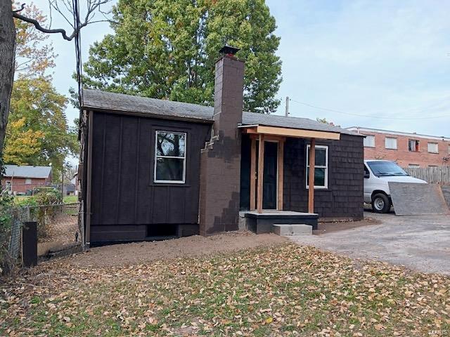 view of front facade featuring board and batten siding, fence, and a chimney