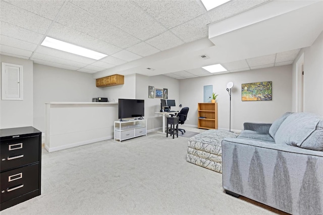 carpeted living area featuring a drop ceiling and baseboards