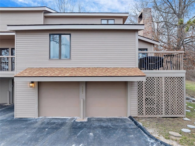 view of side of property with an attached garage, driveway, and a shingled roof