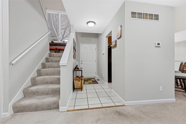 foyer featuring baseboards, stairs, visible vents, and carpet flooring