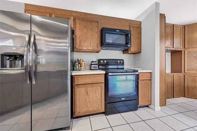 kitchen with brown cabinets, black appliances, light tile patterned floors, and light countertops