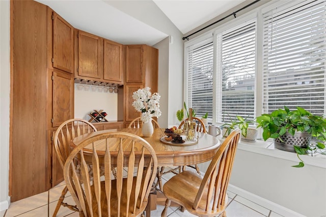 dining area featuring light tile patterned floors and vaulted ceiling