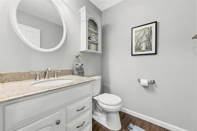 half bath with wood finished floors, vanity, toilet, and baseboards