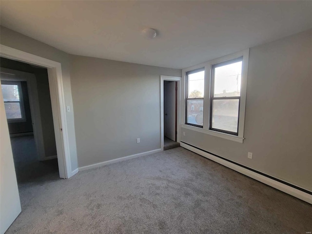 spare room with carpet floors, a baseboard radiator, and baseboards