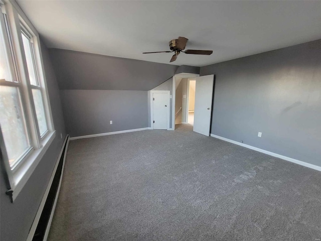 unfurnished bedroom featuring baseboards, lofted ceiling, ceiling fan, baseboard heating, and carpet floors