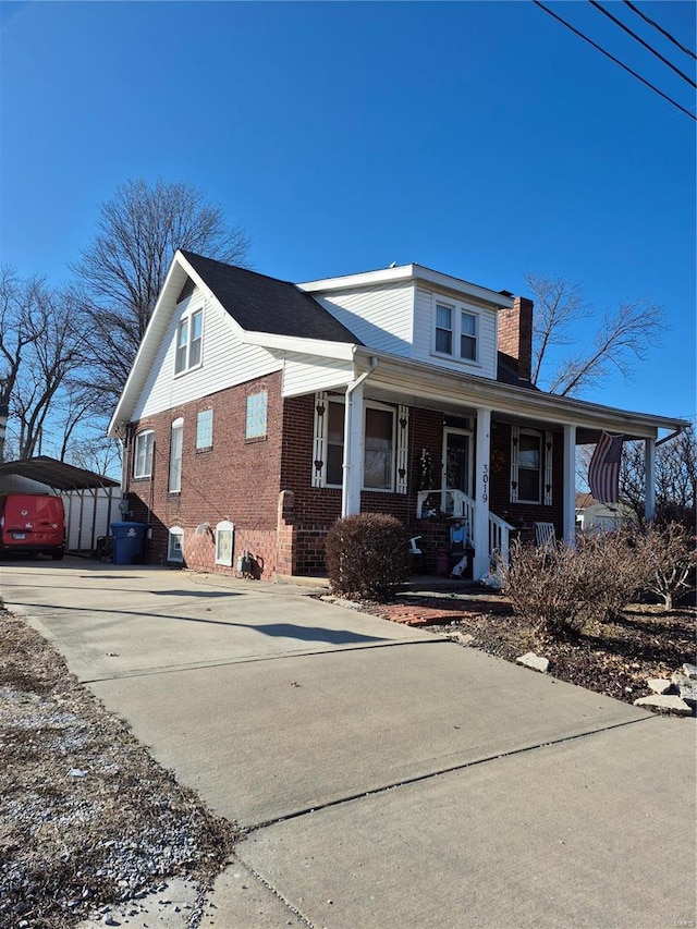 bungalow-style home with a porch, brick siding, and a chimney