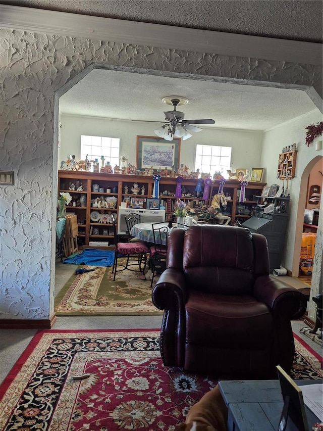 living room featuring a ceiling fan, arched walkways, and a textured ceiling