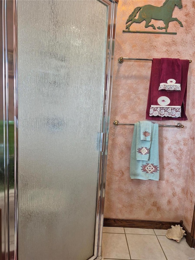 full bath featuring baseboards, tile patterned flooring, and a shower stall