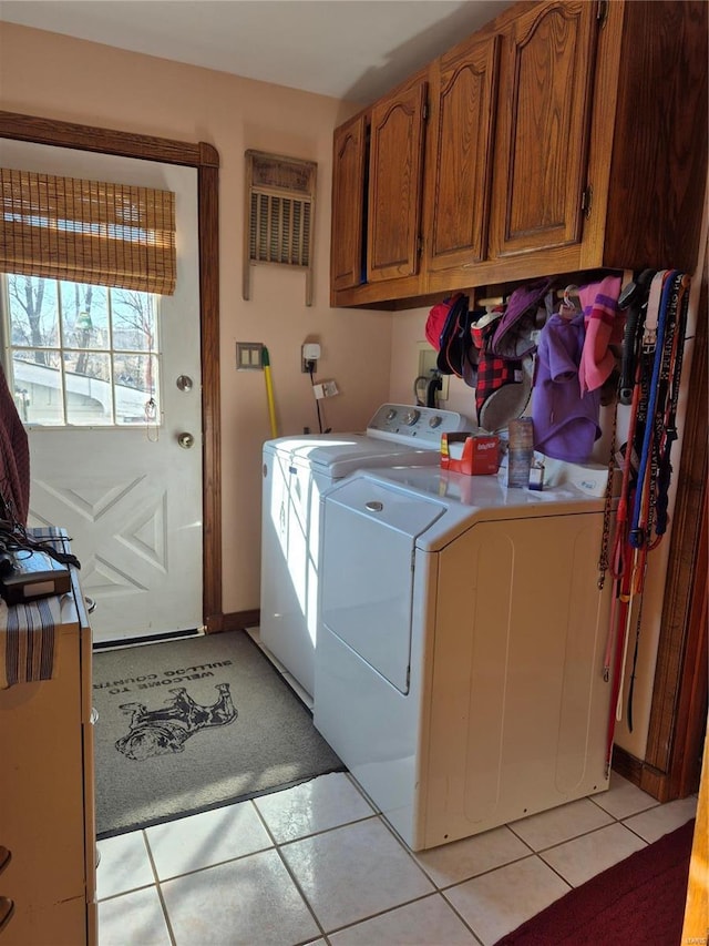 laundry area featuring cabinet space, washing machine and dryer, and light tile patterned floors