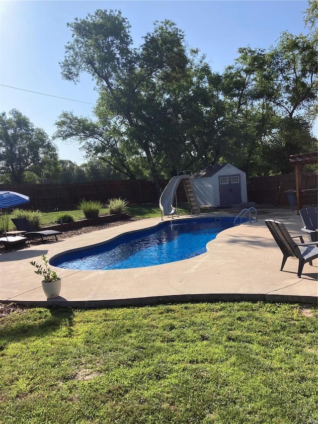 view of pool featuring a storage unit, a water slide, a patio area, and a fenced backyard