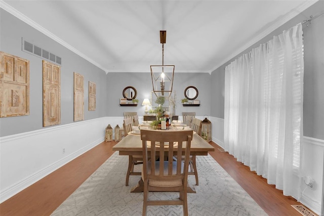 dining area with crown molding, visible vents, and wood finished floors