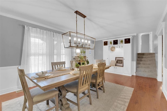 dining area with stairs, ornamental molding, a fireplace, and wood finished floors