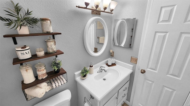 bathroom featuring toilet, a textured wall, a chandelier, and vanity