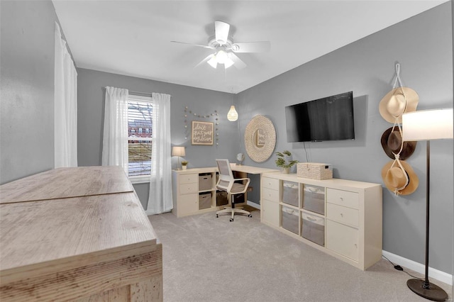 home office with baseboards, a ceiling fan, and light colored carpet