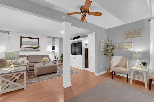 living area with light wood-style floors, baseboards, a ceiling fan, and ornate columns