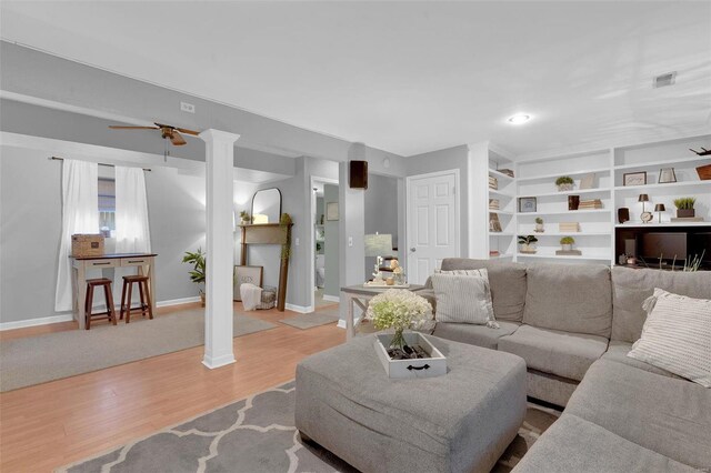 living room with decorative columns, visible vents, ceiling fan, wood finished floors, and baseboards