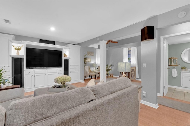 living room with light wood finished floors, baseboards, and visible vents