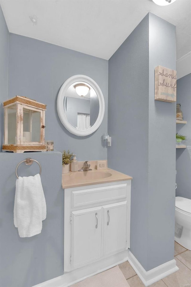 bathroom featuring vanity, tile patterned flooring, toilet, and baseboards