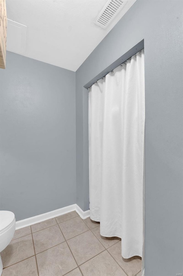 bathroom with toilet, baseboards, visible vents, and tile patterned floors