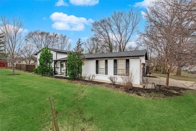 ranch-style house with brick siding, fence, a front lawn, and roof with shingles