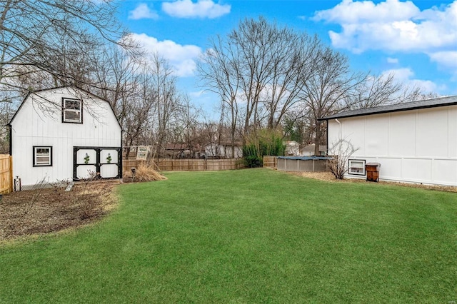 view of yard with a barn, fence, a fenced in pool, and an outbuilding